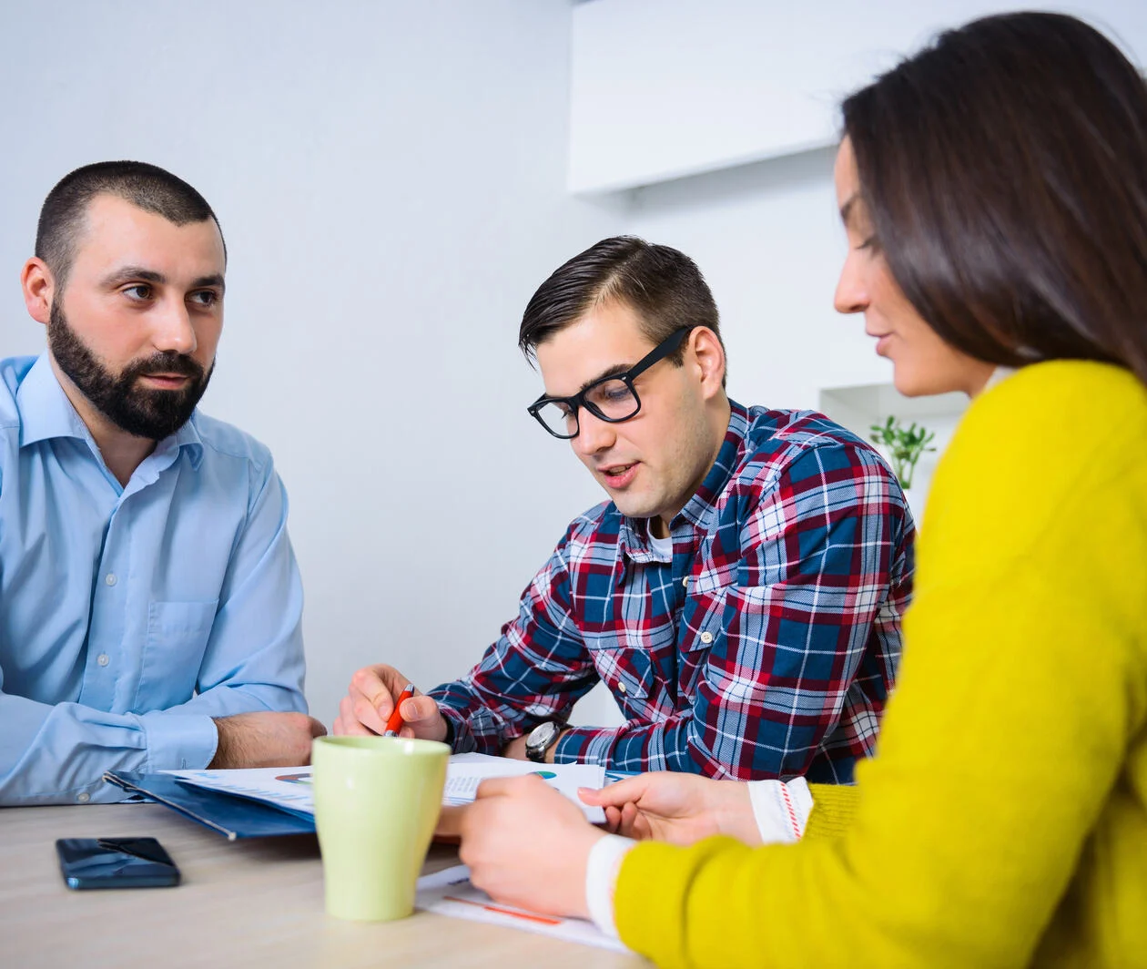 Group of diverse people sat at a table discussing paperwork.