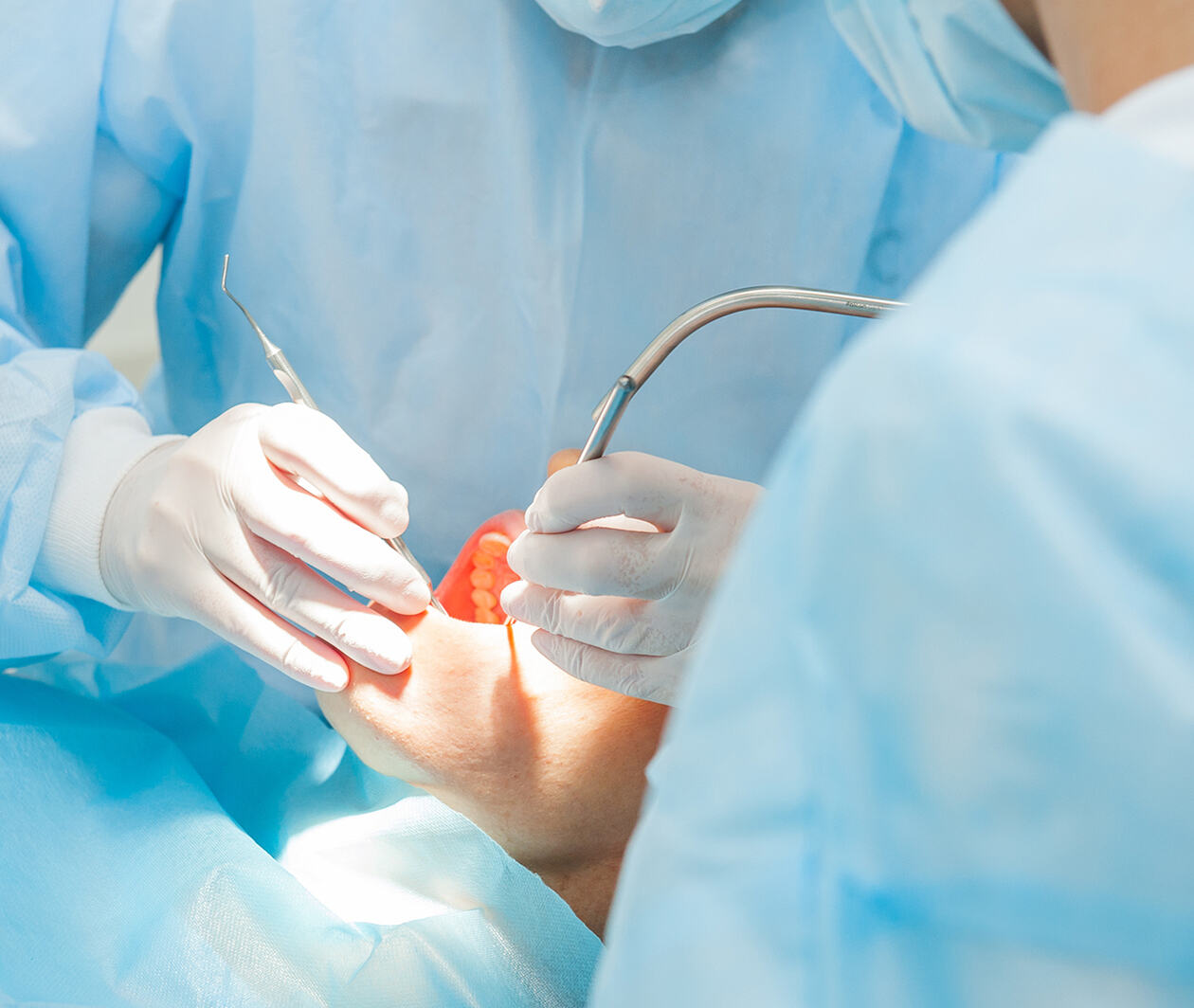 Dentists use medical equipment to clean patients' teeth