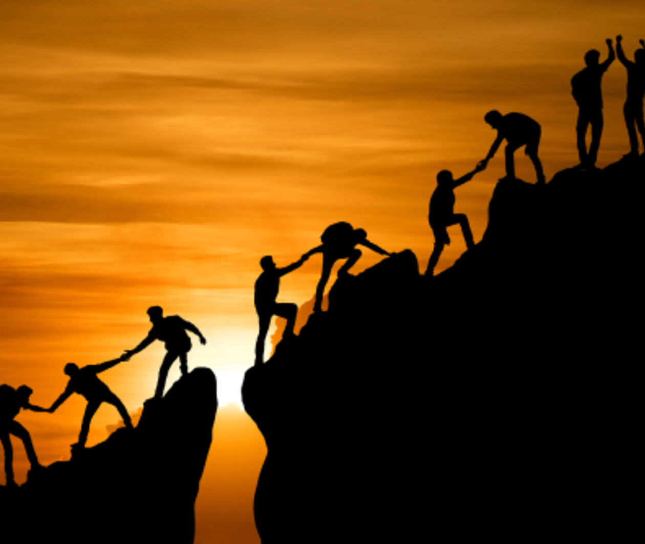 group of people on peak mountain, helping each other to the top