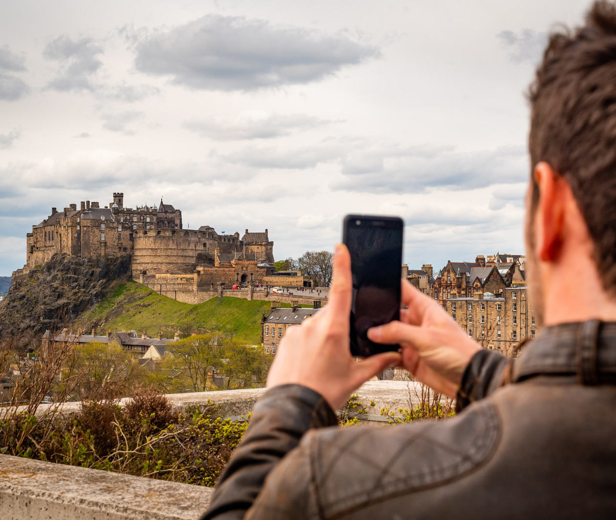 Man taking picture of Edinburgh Castle using mobile phone