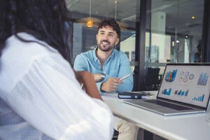 A man and a woman at a desk in an office analysing data. 