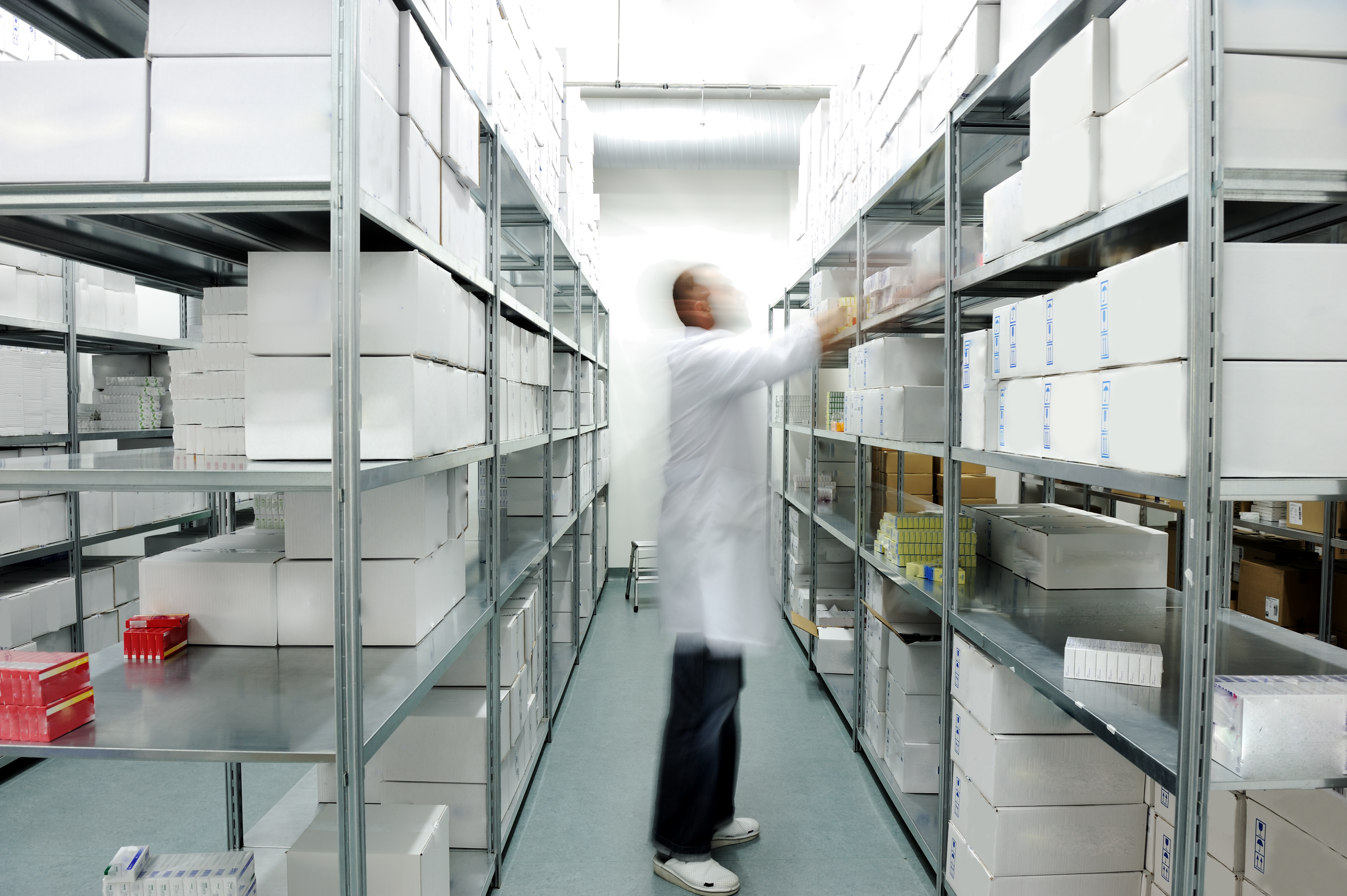 Worker putting boxes together on shelves in modern warehouse