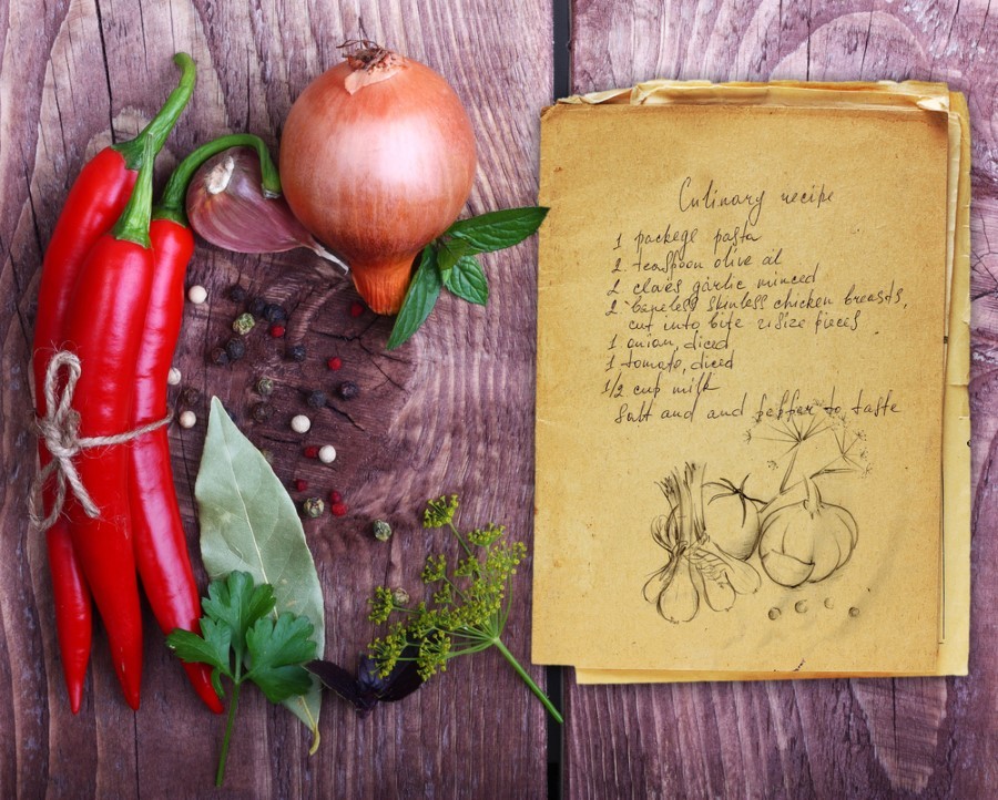 Some raw vegetables beside a handwritten recipe on a wooden table