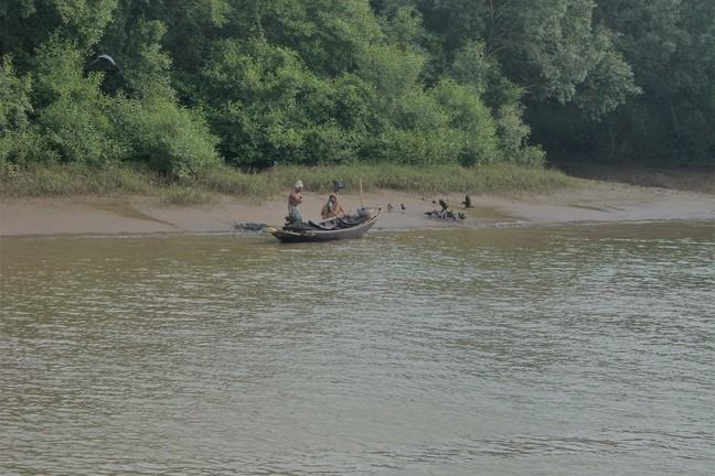 Two men with small boat the side of a river