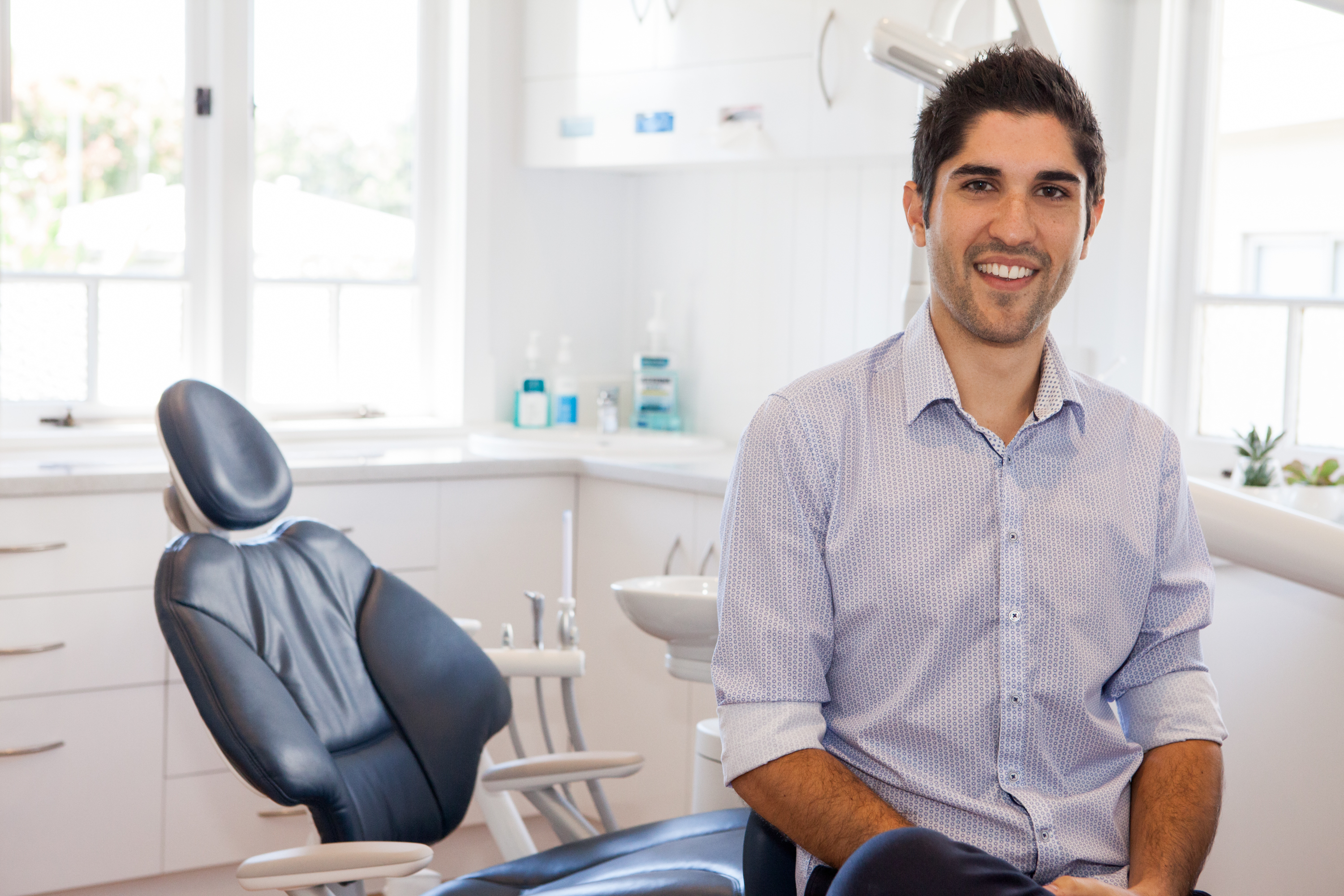 A friendly dentist smiles to the camera.