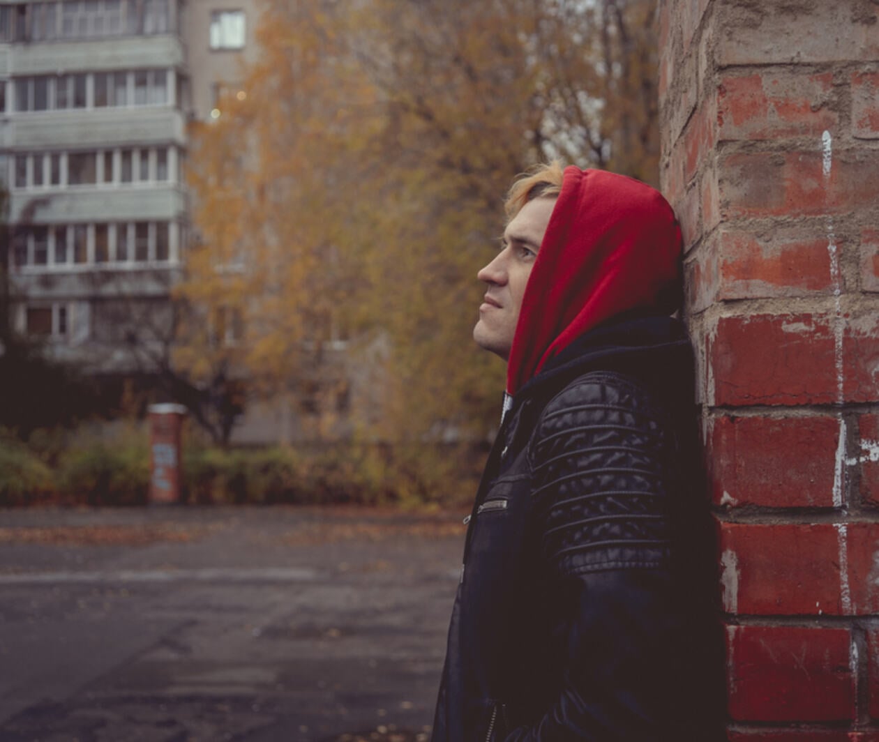 Young man in hoodie leans against wall