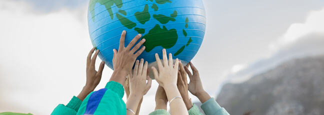 Group of people holding up an inflatable globe.
