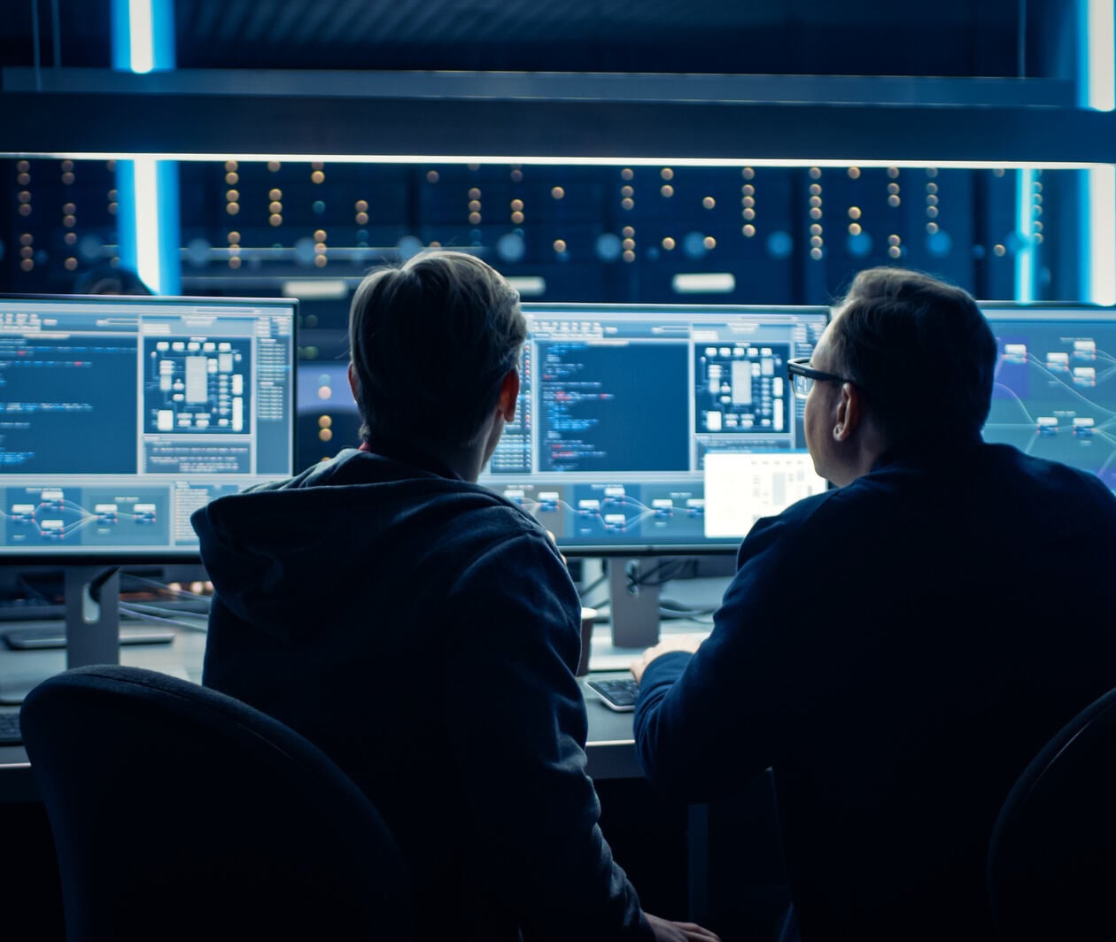 Two Professional IT Programers Discussing Blockchain Data Network Architecture Design and Development Shown on Desktop Computer Display. Working Data Center Technical Department with Server Racks