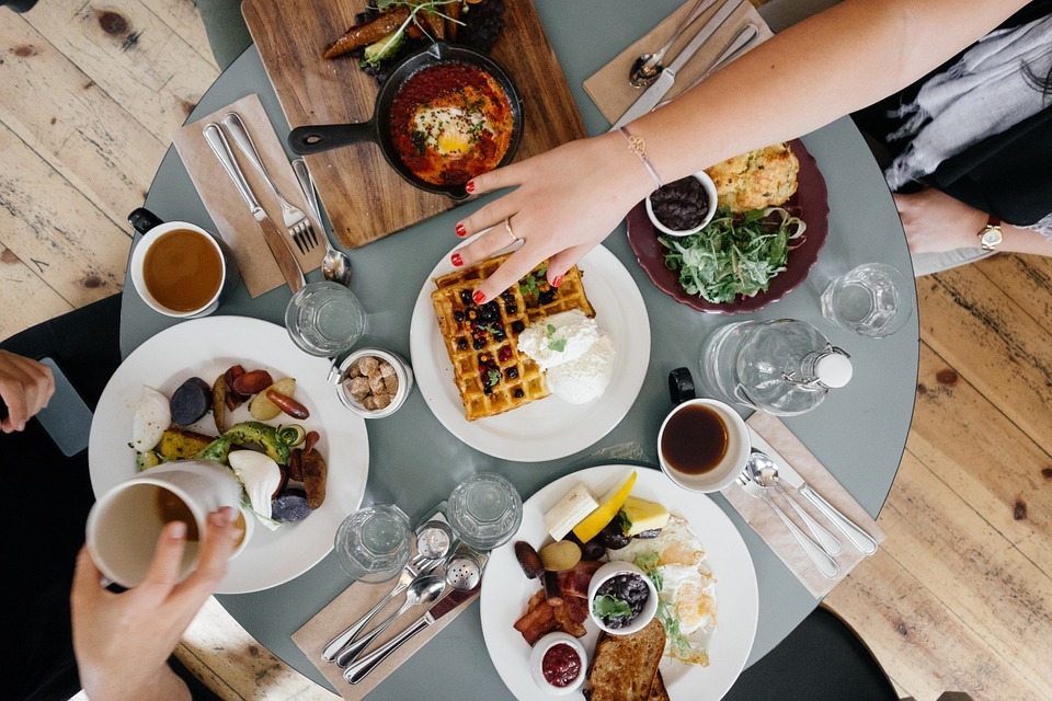 Aerial view of a round table with breakfast food on it with 2 people sitting