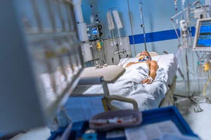 A patient in a hospital bed, connected to various machines