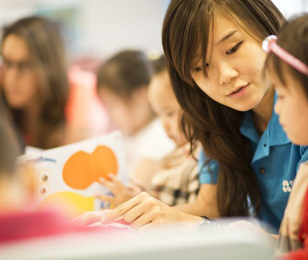 Teacher sitting with young pupil, giving instructions