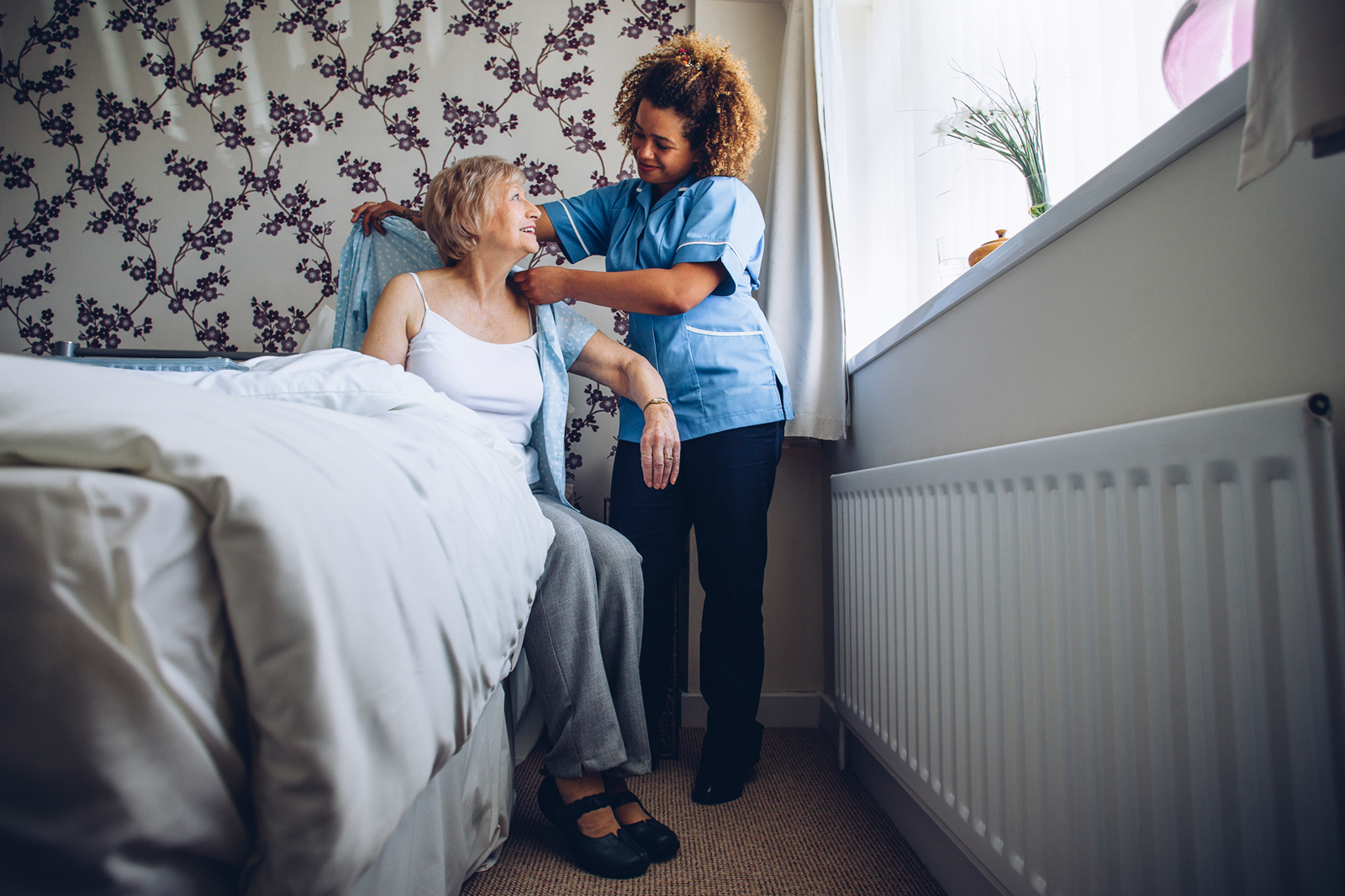 Care worker helping an elderly woman to dress