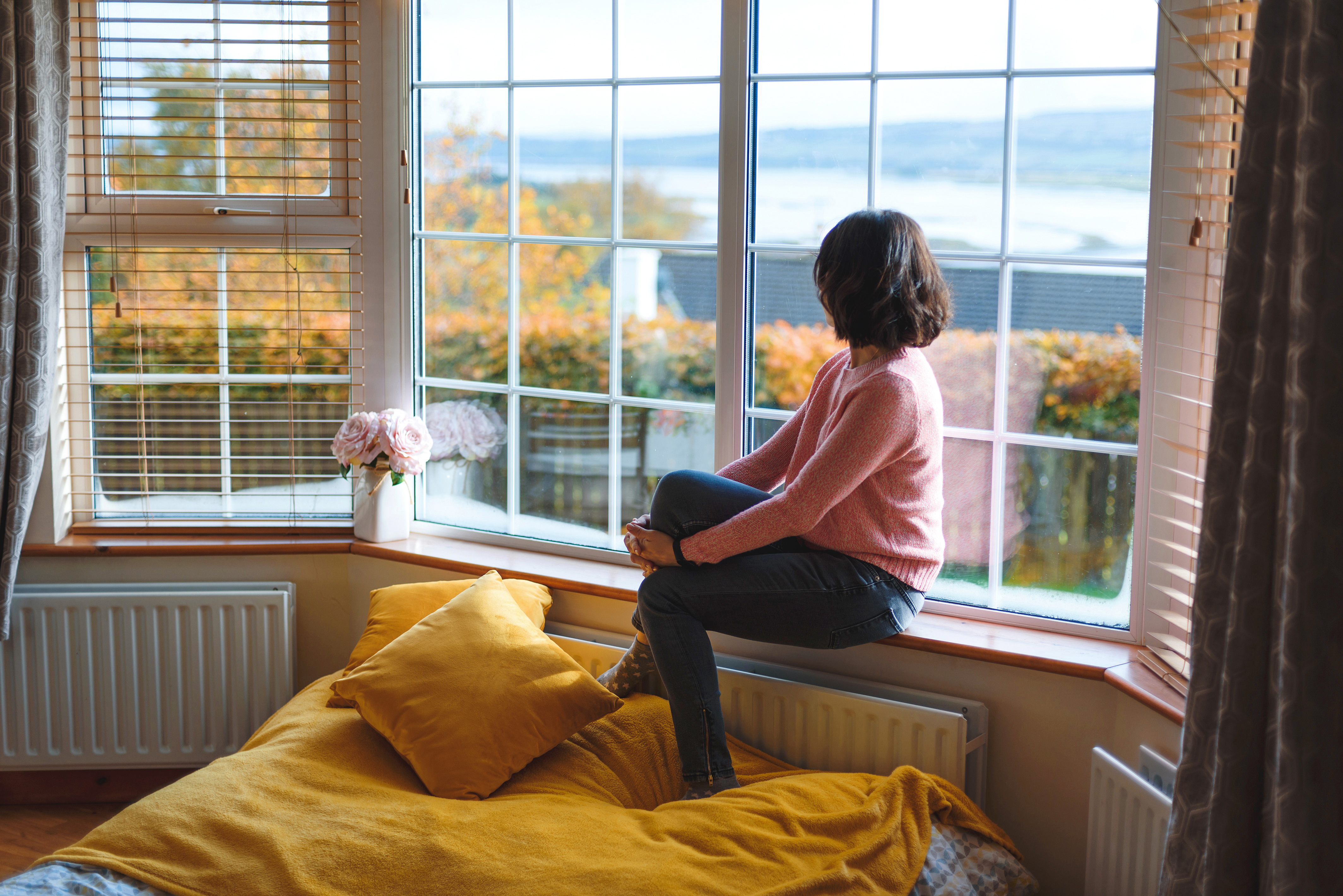 Woman sitting on a windowsill and looking out the window