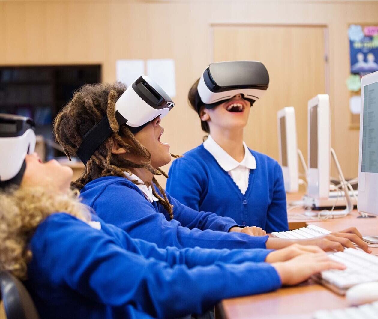 Three children in blue school uniform hysterically laugh as they play with a Virtual Reality headset.