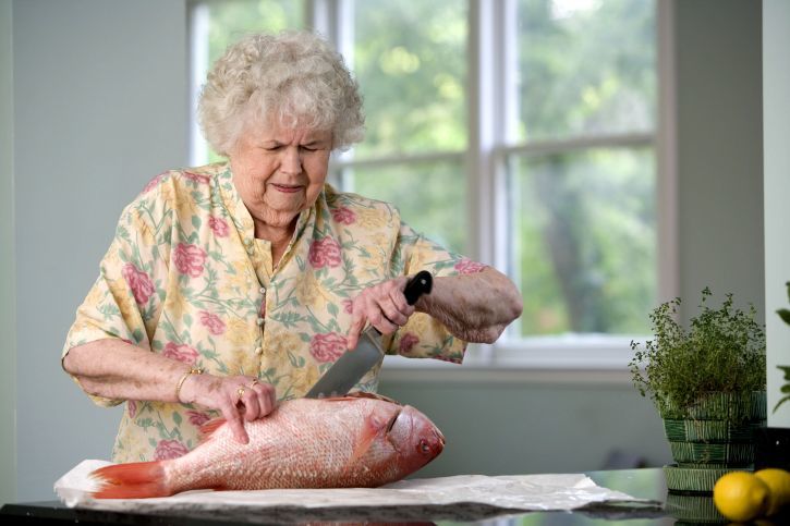 An elderly woman filleting a fresh fish