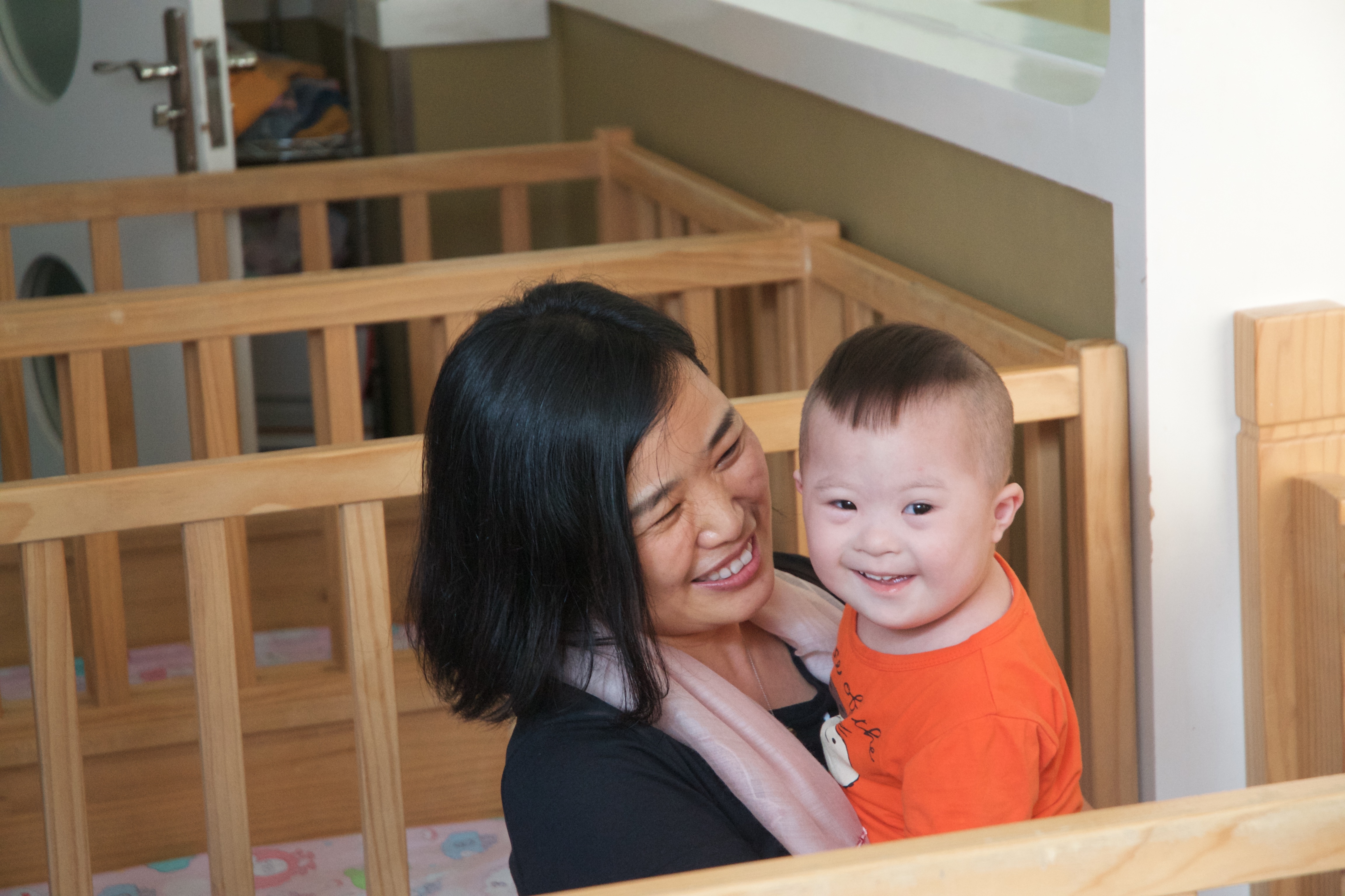 A woman holding a young child. Both the woman and child are smiling.