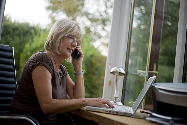 Photo of a woman using her laptop while on the phone