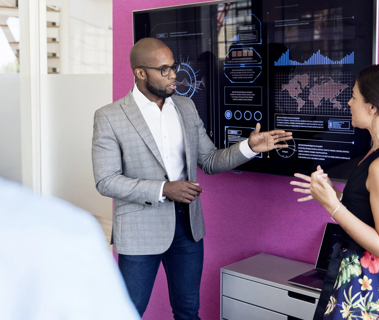 Businessman and woman using graphs on screen in meeting