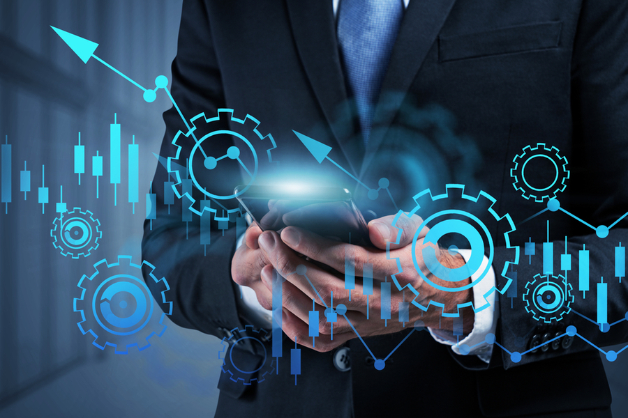 Business man holding a tablet in both hands. The image is overlaid with graphics of cogs, graphs, arrows