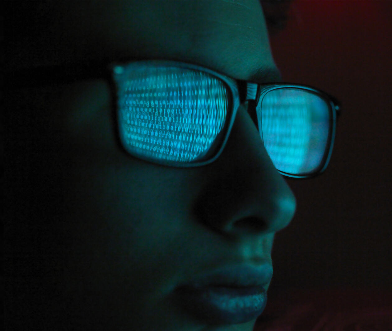 Reflection in spectacles of virus hacking a computer, close up of a male face representing cybersecurity.