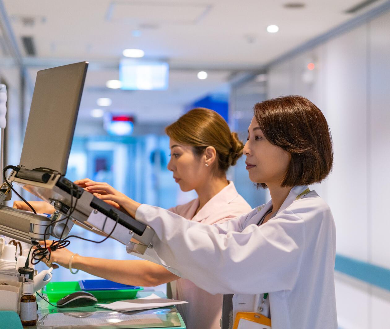 Two women, hospital staff working on computers in the hospital hallway