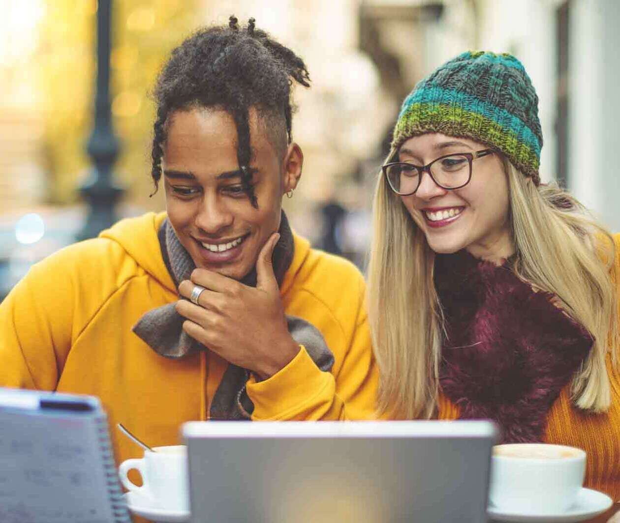 Men and women looking at a screen and sharing notes while smiling