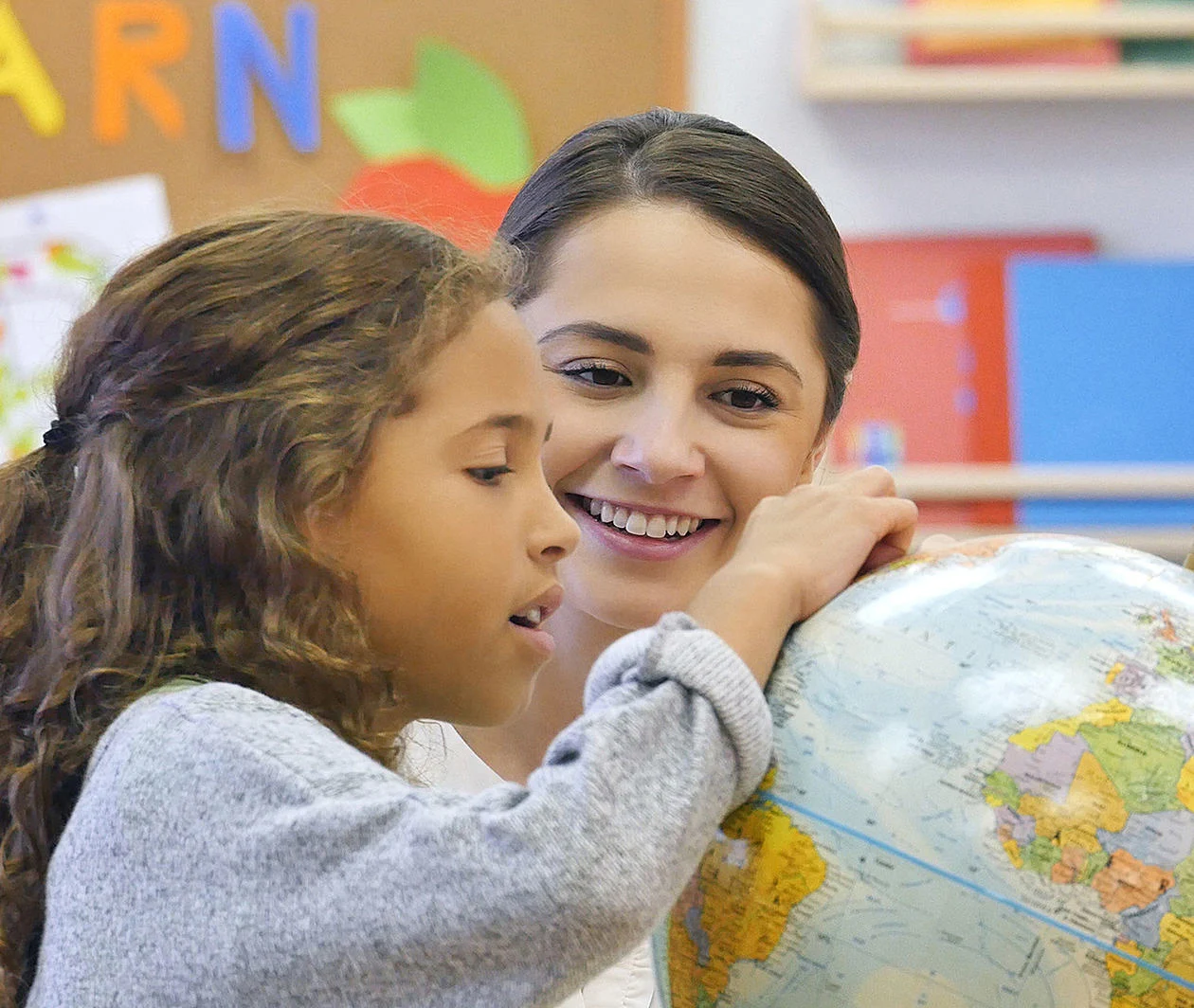 a teacher and a student looking at a globe