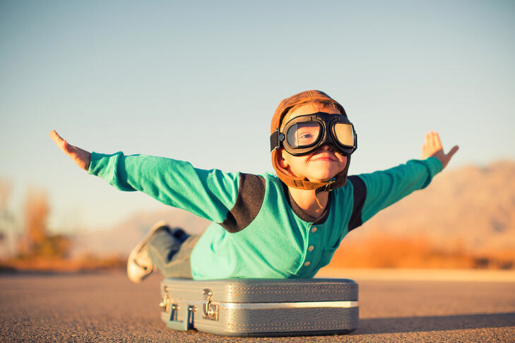 a boy standing on a suitcase