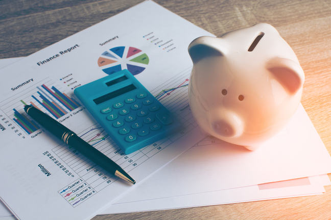Piggy bank, calculator, pen and graphs