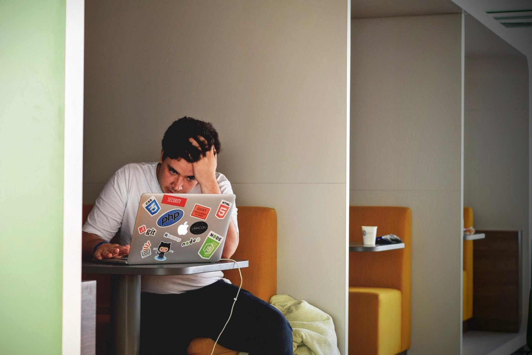 A young man looking confusingly at a laptop