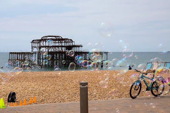 Bubbles move across a seafront with a burnt-out pier in the background.