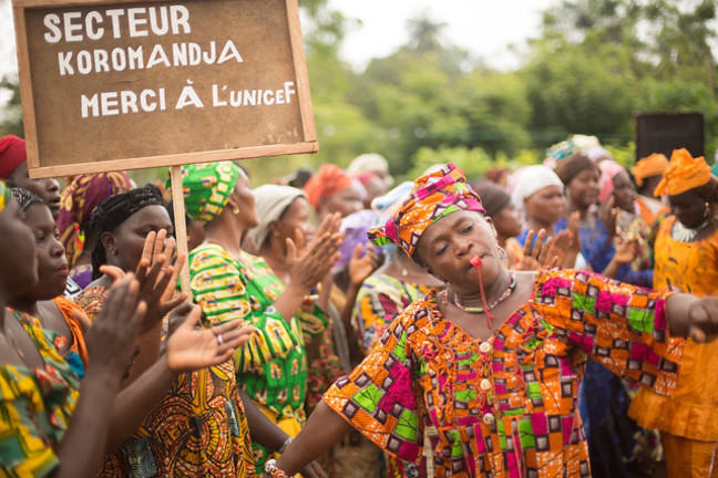 Women in colourful dress are seen dancing in celebration.