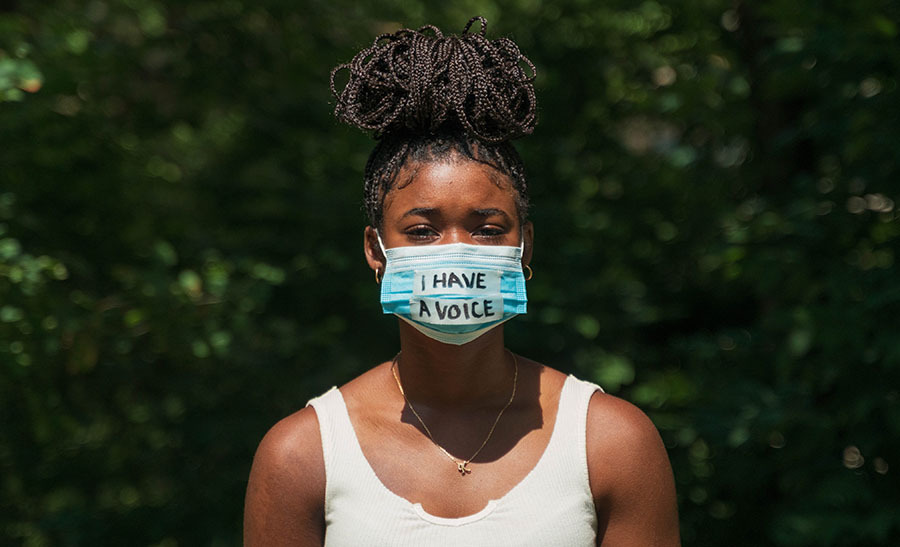 Young. black woman wearing mask with words 'I have a voice'