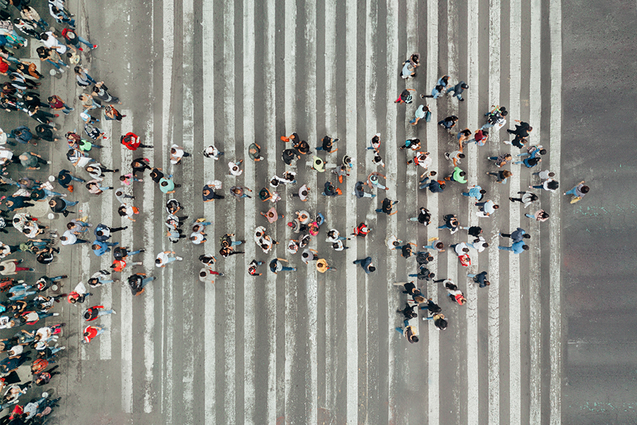 Aerial view of pedestrians walking in the formation of an arrow pointing forward.