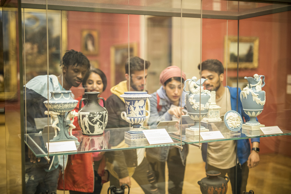 5 students standing in a museum looking at artefacts in a glass cabinets