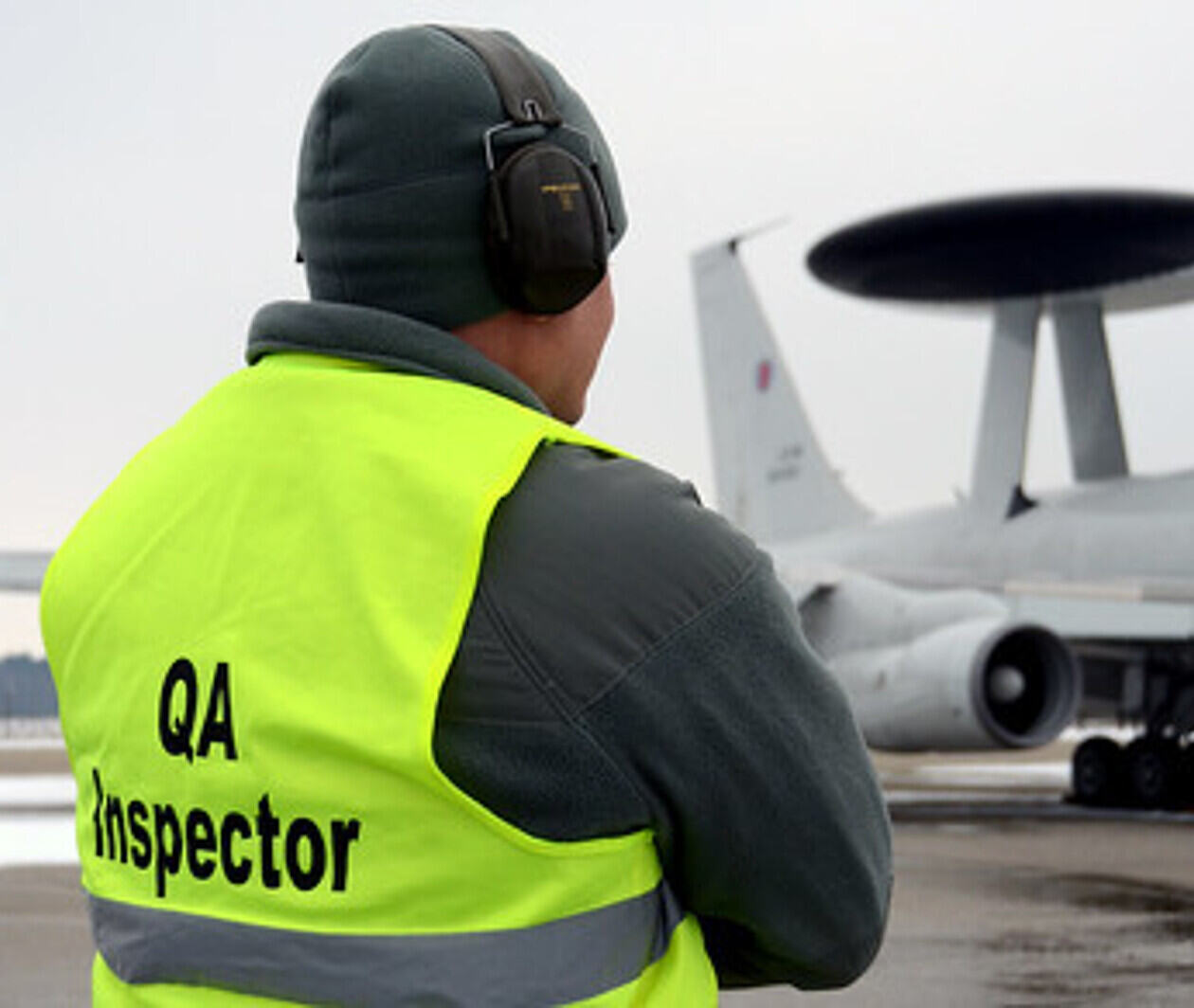 Man in high-vis jacket watching an airplane.