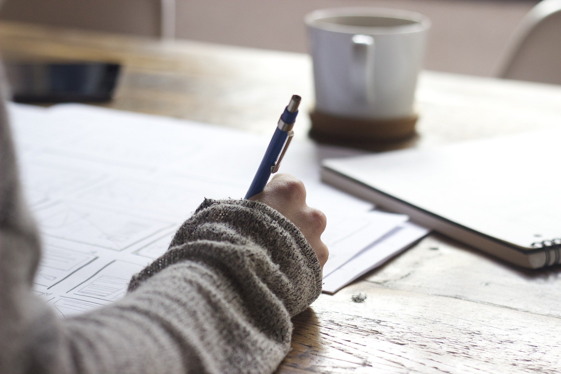 A person holding a pen and writing in a notebook.