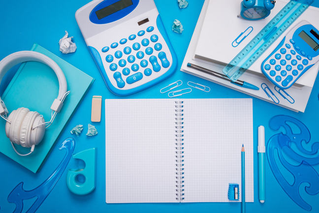 Open spiral notebook with stationery and headphones on light blue background