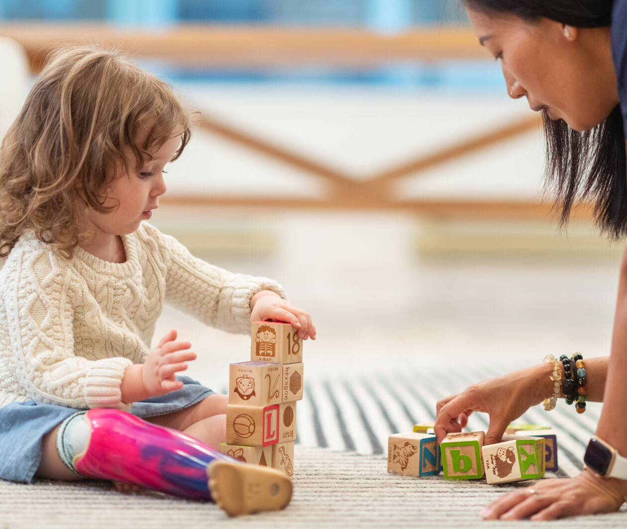 Young girl with prosthetic leg, learning and developing with building blocks