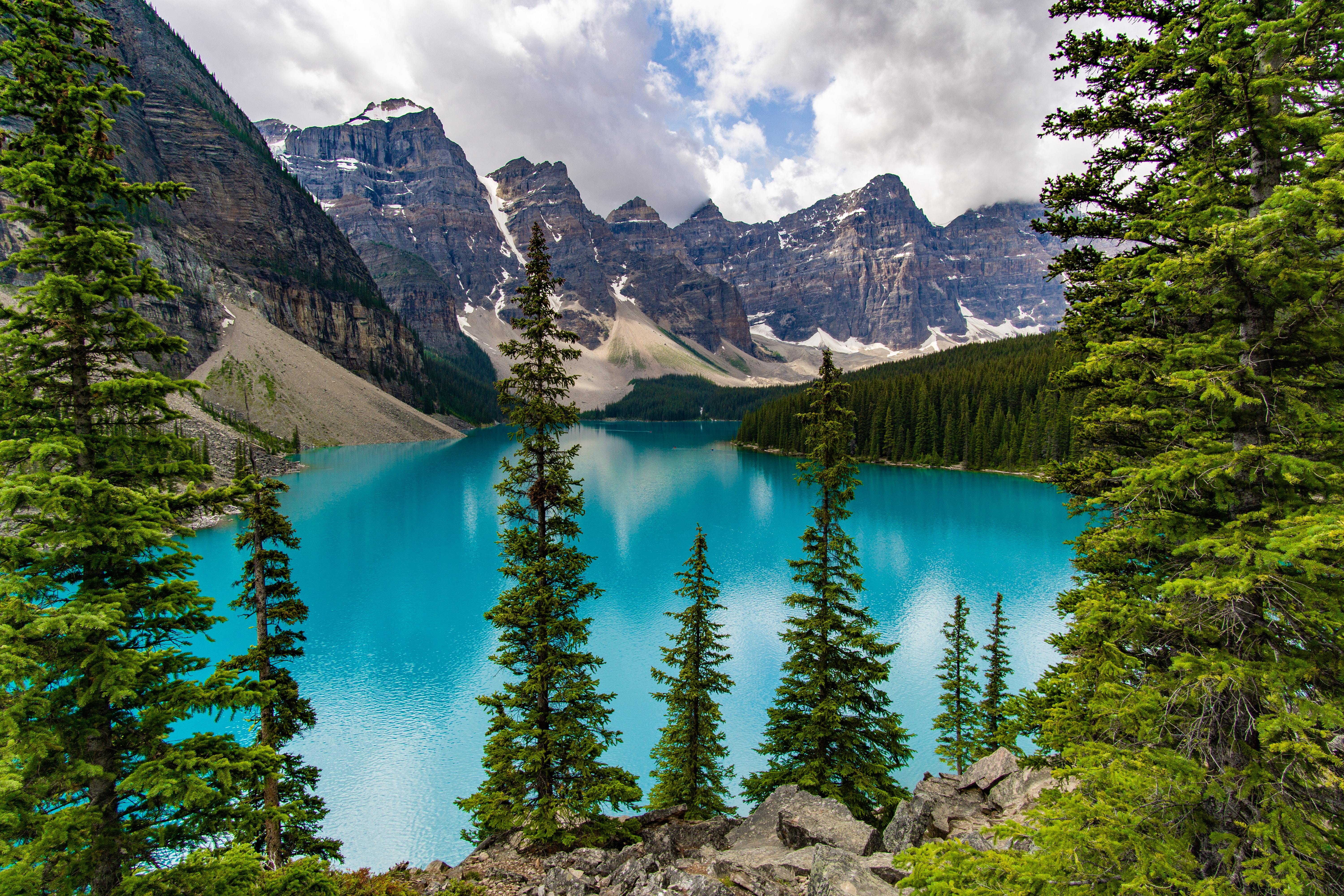 Image of turquoise lake with mountains in the background.