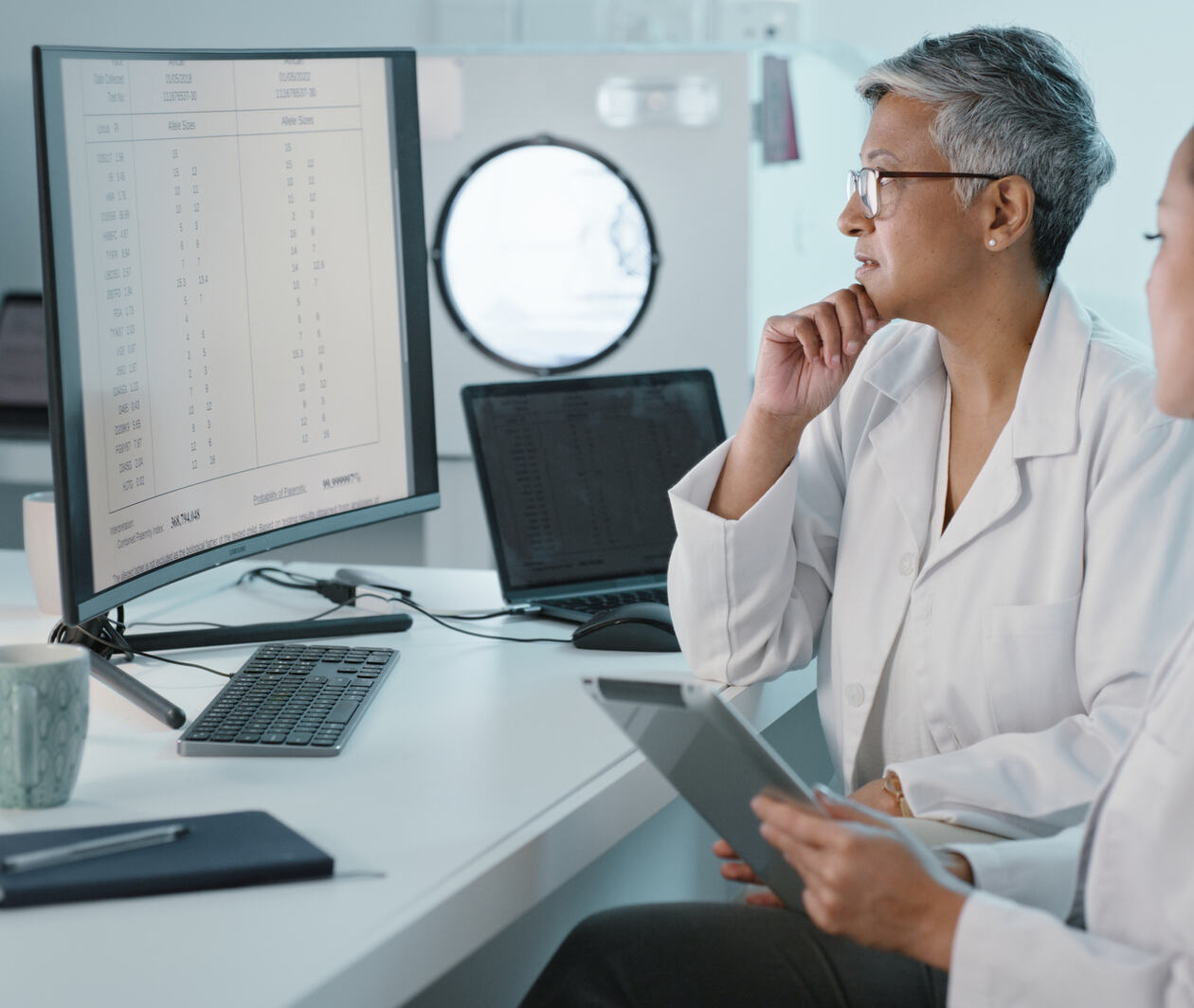 Two doctors analysing data on a computer screen.