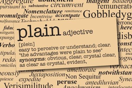 background shows a page of a dictionary, with the word 'plain' and its definition in the foreground. The definition says 'easy to perceive or understand; clear'