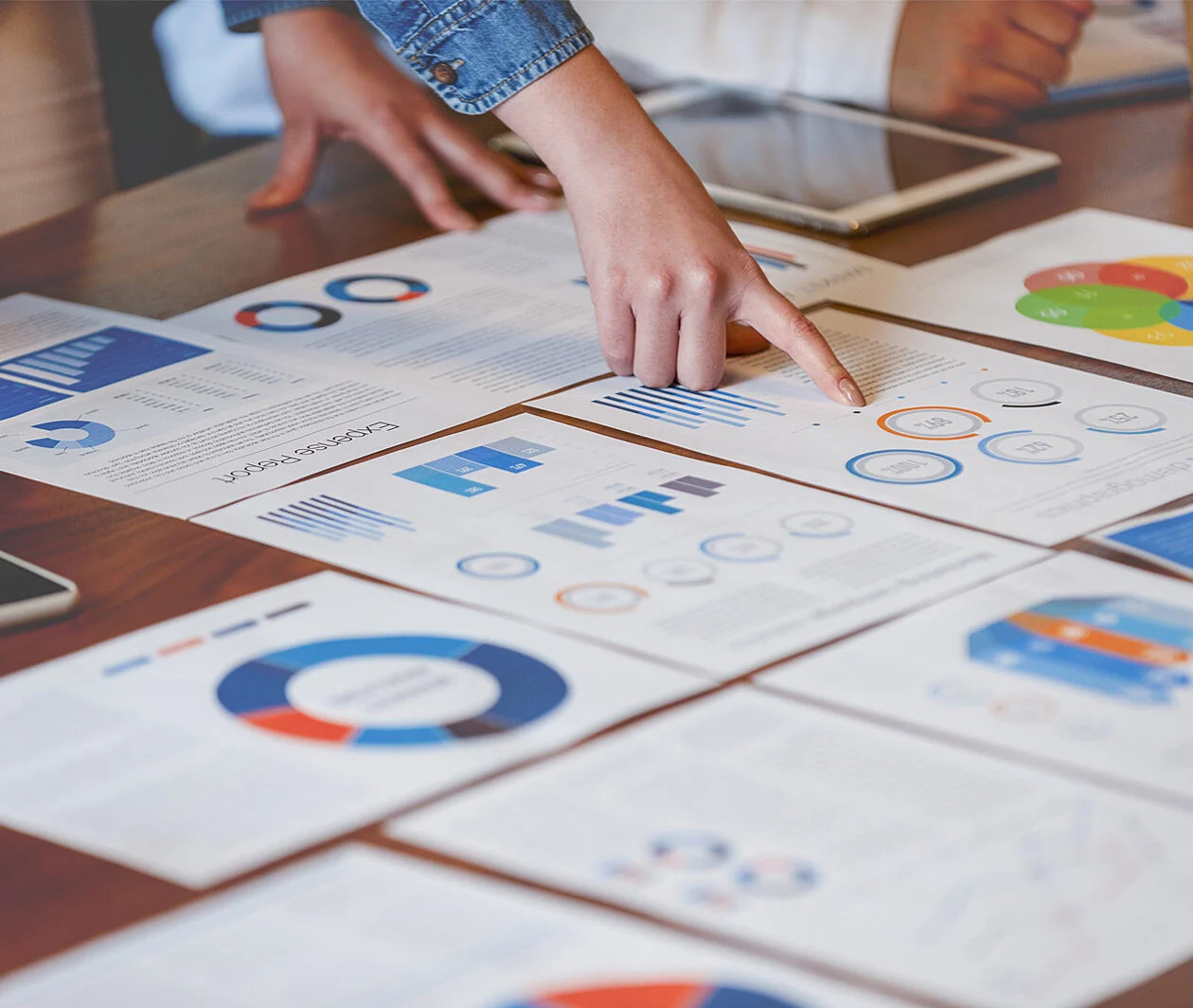 Someone pointing at a chart on a piece of paper on a desk.