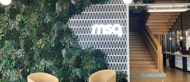 MSQ sign above a wall of grass overhanging two chairs in a reception area