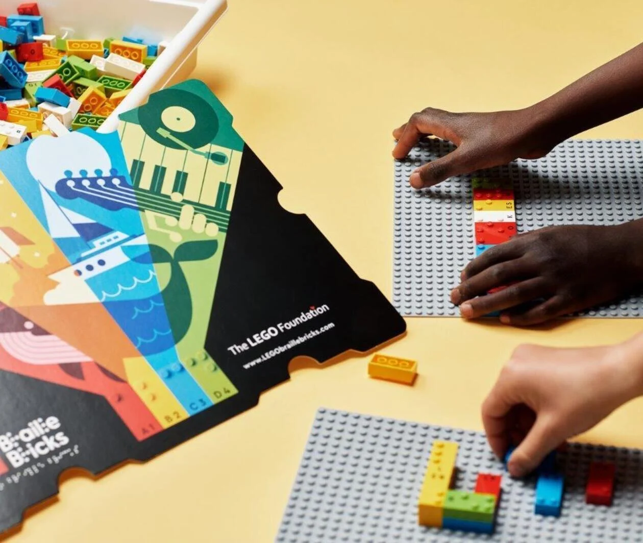 Mains de deux enfants jouant avec des LEGO Braille bricks