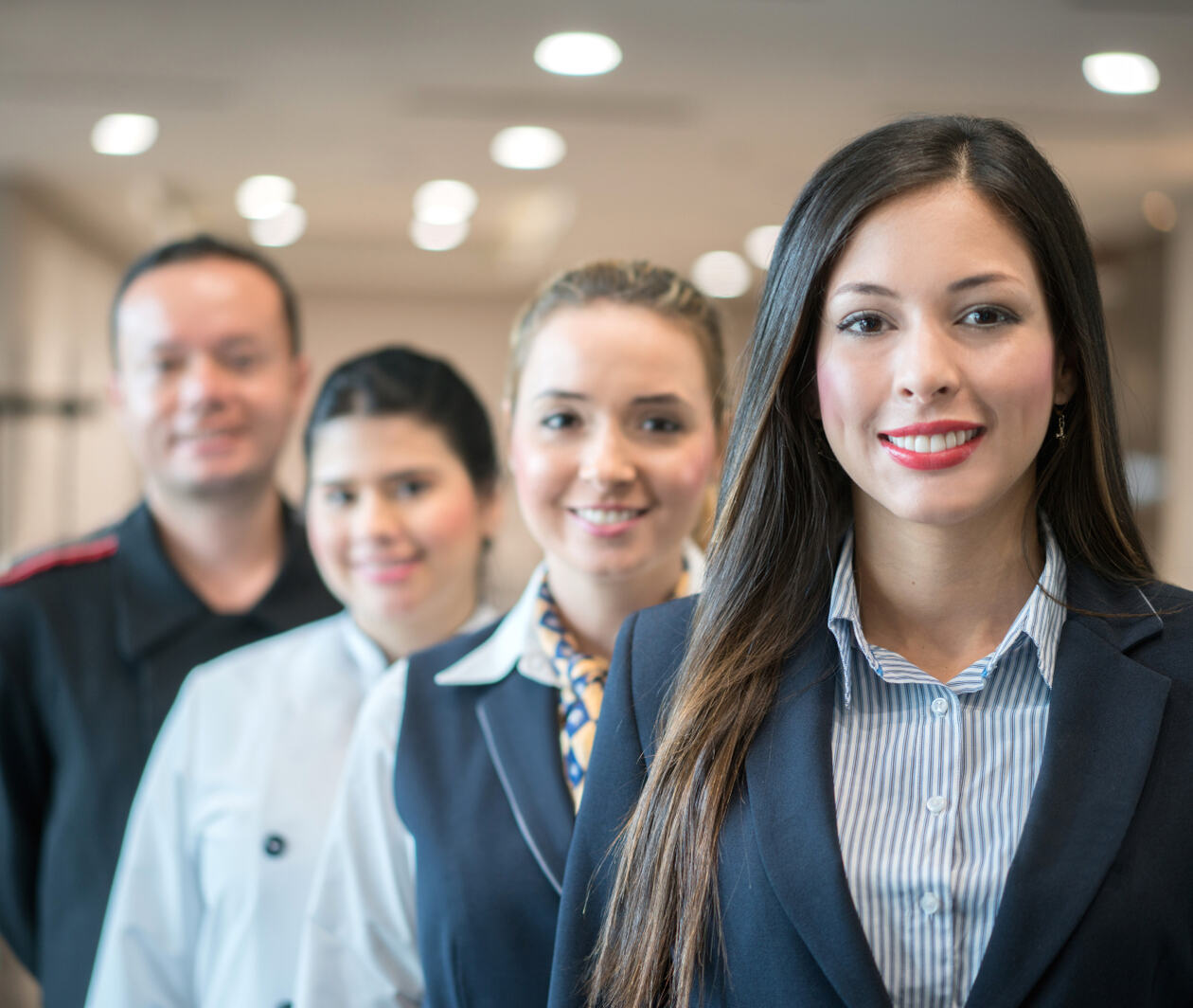 Group of four hotel workers stood together including a chef and concierge.