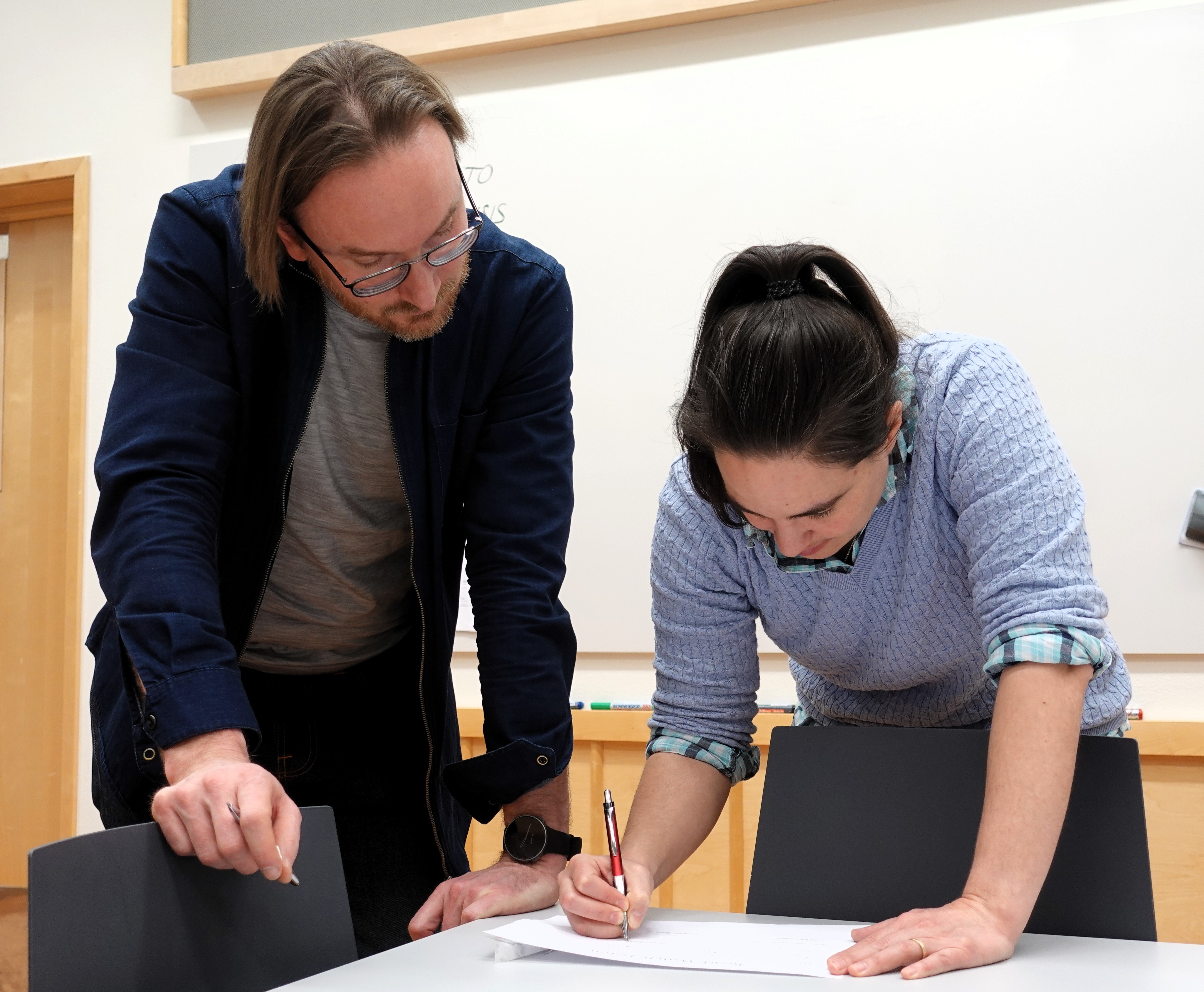 Two person looking at a document.