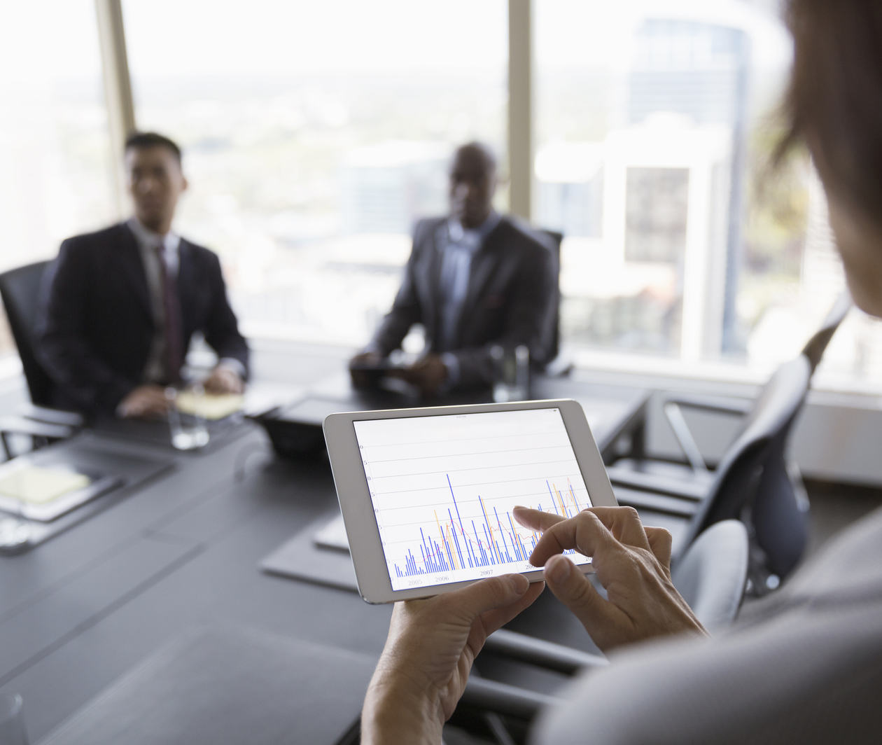 Businesswoman viewing bar chart on digital tablet in conference room meeting.