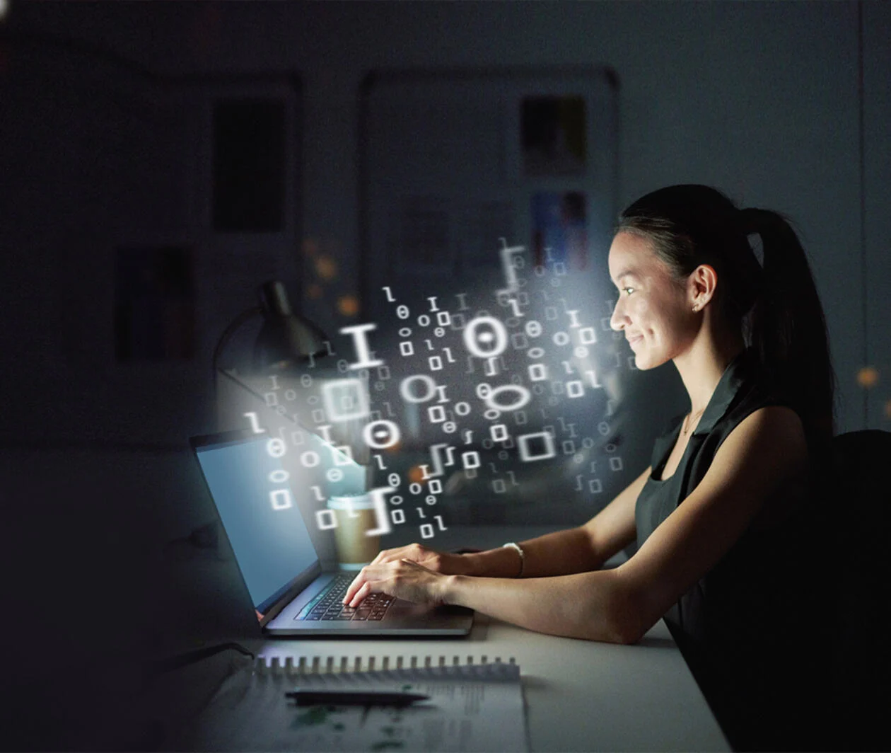 woman looking at a laptop while typing and smiling.