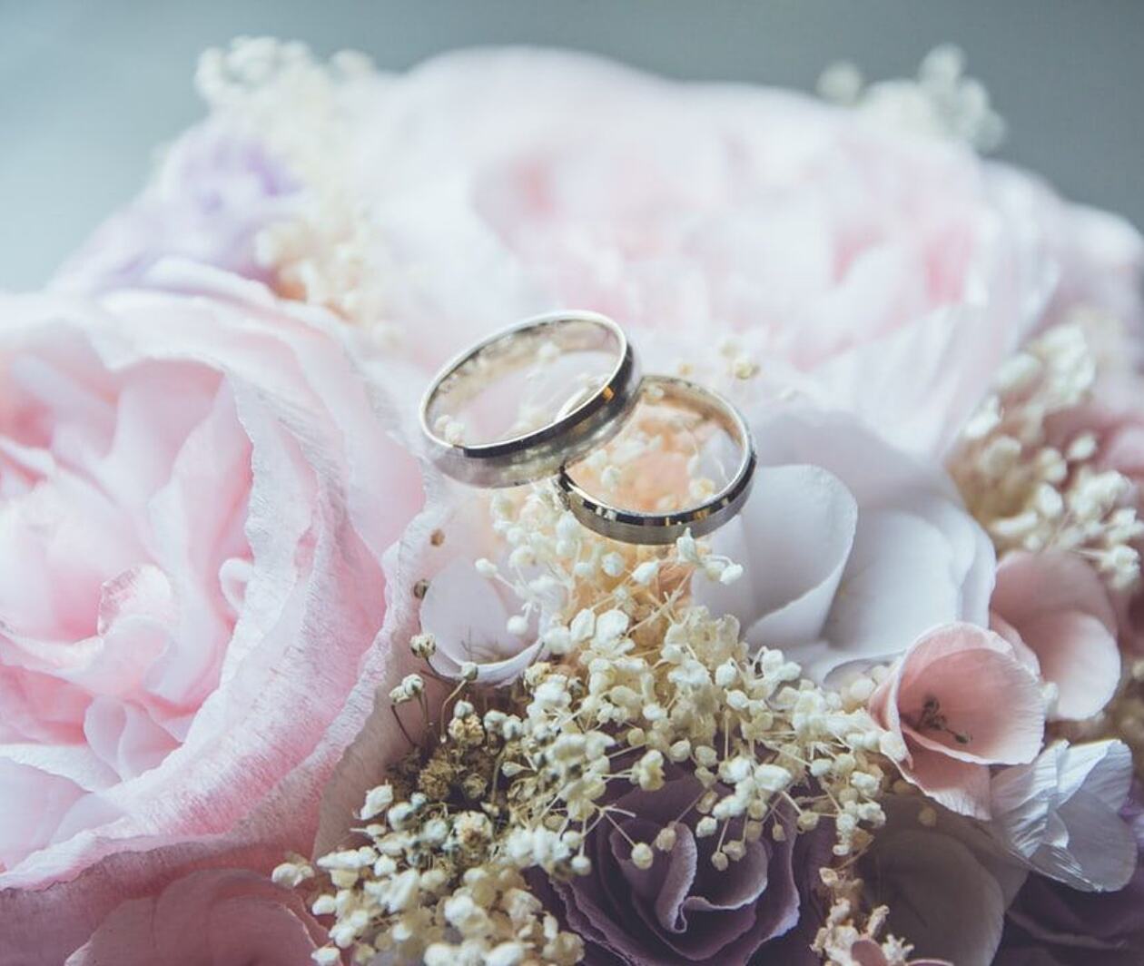 Two gold wedding rings sat on top of a bouquet of pink flowers